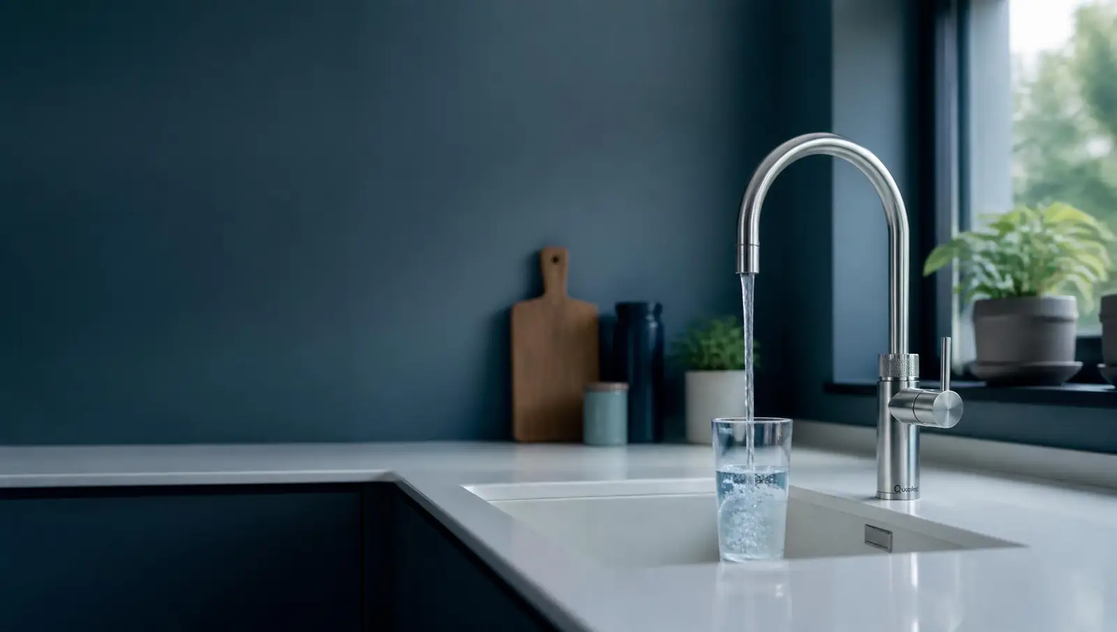 Filtered water pouring from a stainless steel under-sink filter tap into a glass in a modern British kitchen